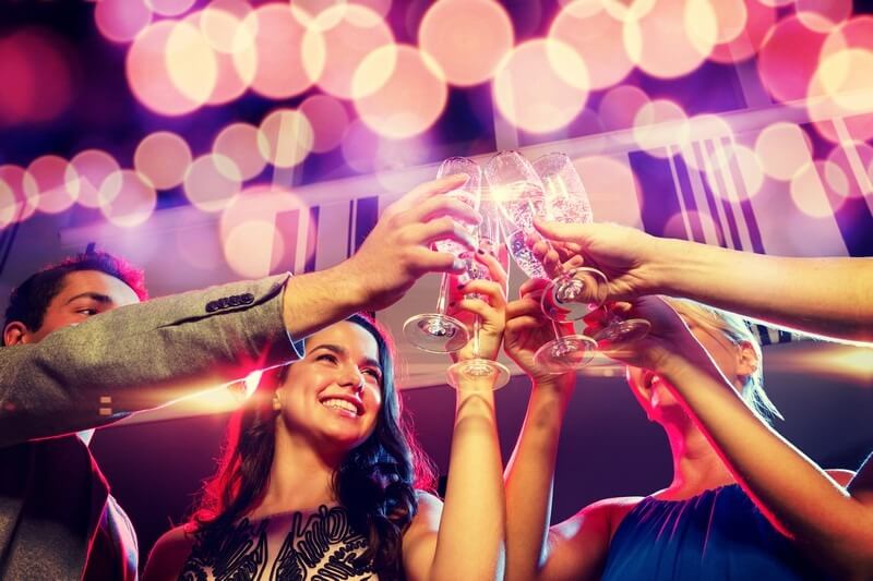 smiling friends with glasses of champagne in Bar